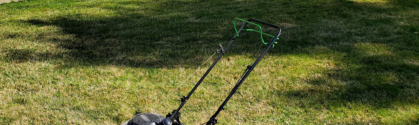 Green lawn mower in the middle of a fresh mown lawn