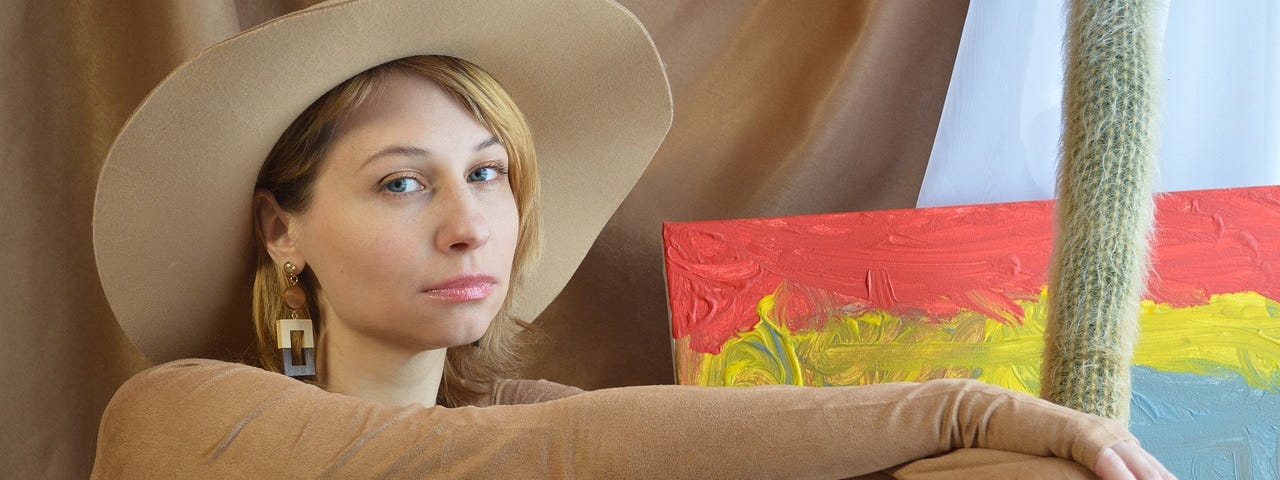 Young woman, model, big hat, blonde hair, leans against a brown leather suitcase, travel