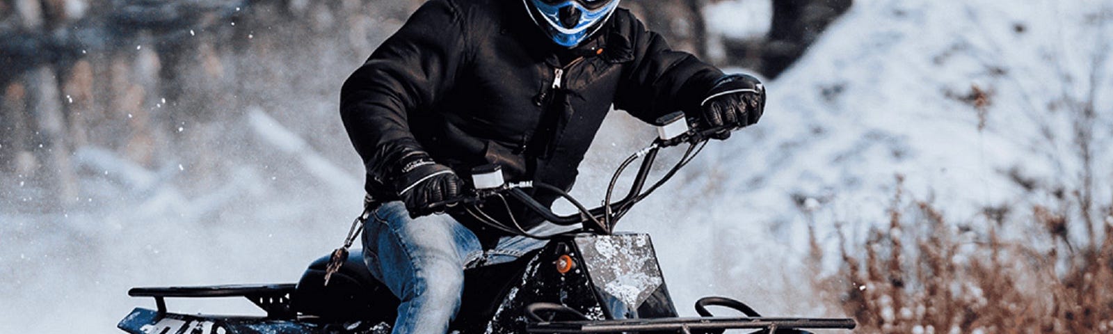 A Reever Electric ATV being ridden through snow covered backroads.