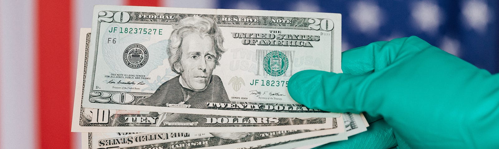 A gloved hand holds money before the American flag