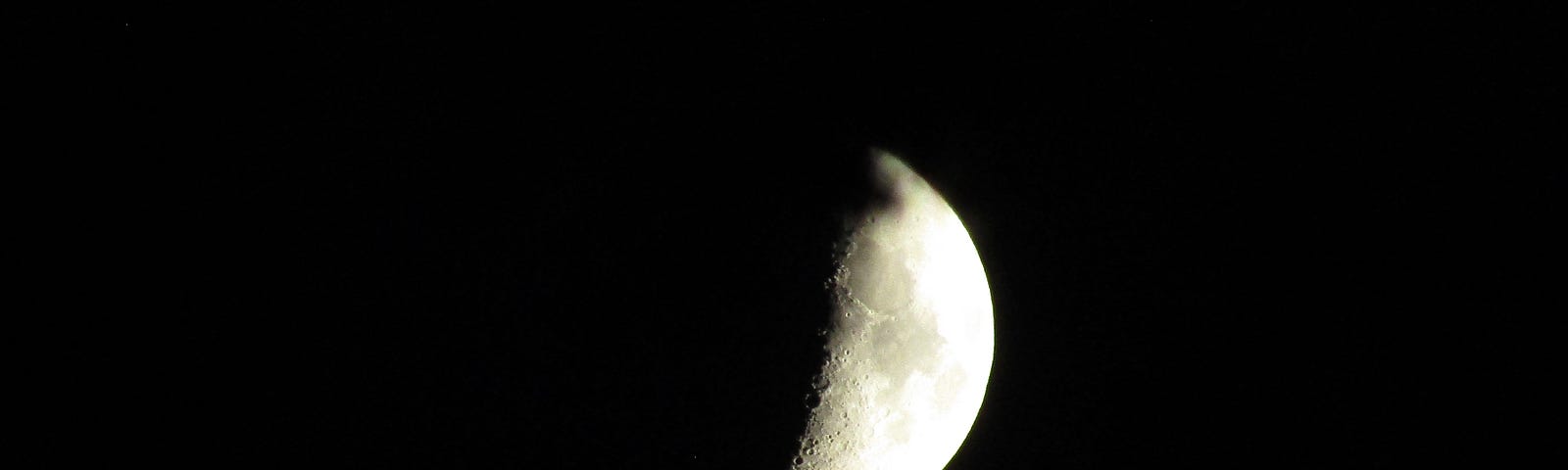 A half moon, slightly obscured by an apparent shadow.