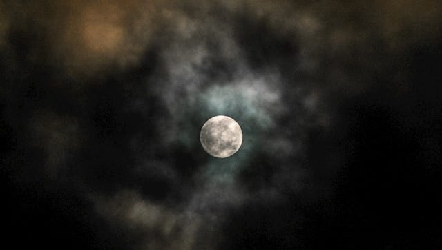 Photo of a full moon on a dark, cloudy sky
