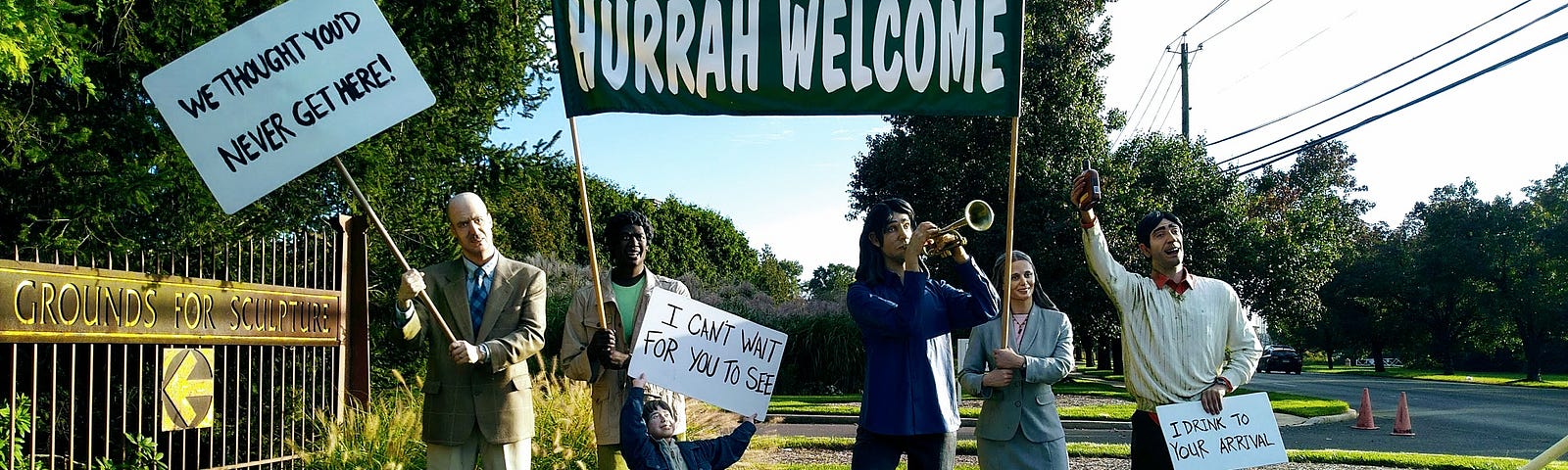 Sculpture of a group of people with welcoming signs at the entrance to the Grounds of Sculpture in Hamilton, New Jersey