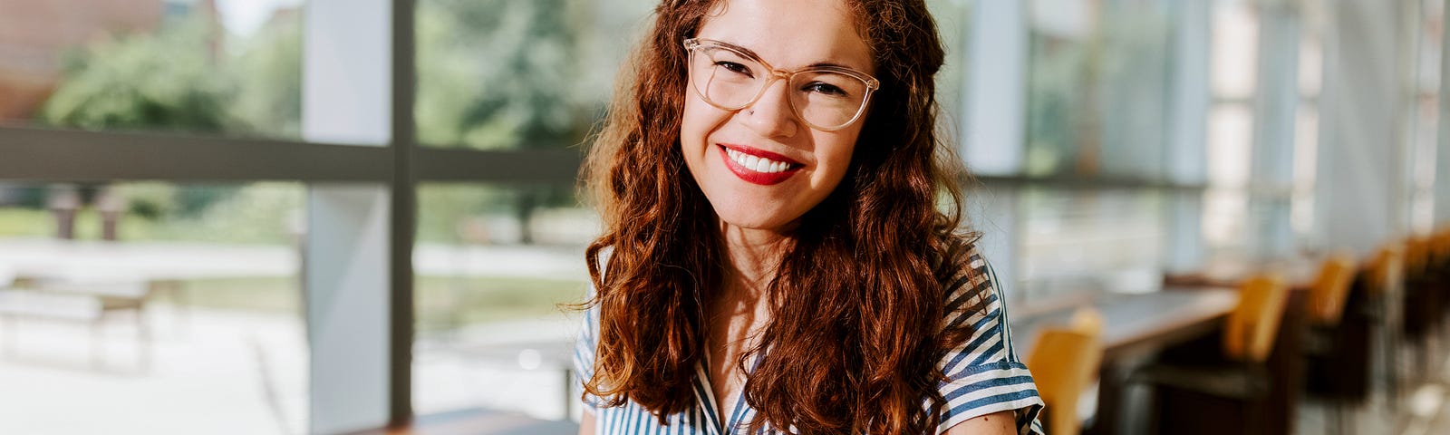 Taylor smiles for a photo near the windows of the College of Business’ Hawks Hall