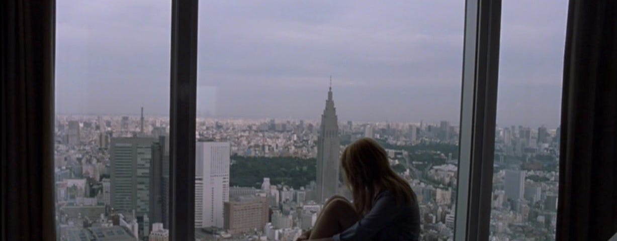Cena do filme estadunidense Lost In Translation (Encontros e Desencontros) de Sofia Coppola. Na cena aparece a protagonista Charlotte sentada encolhida com as mãos á frente do joelho, na beira da janela no alto de um prédio olhando para a fora.