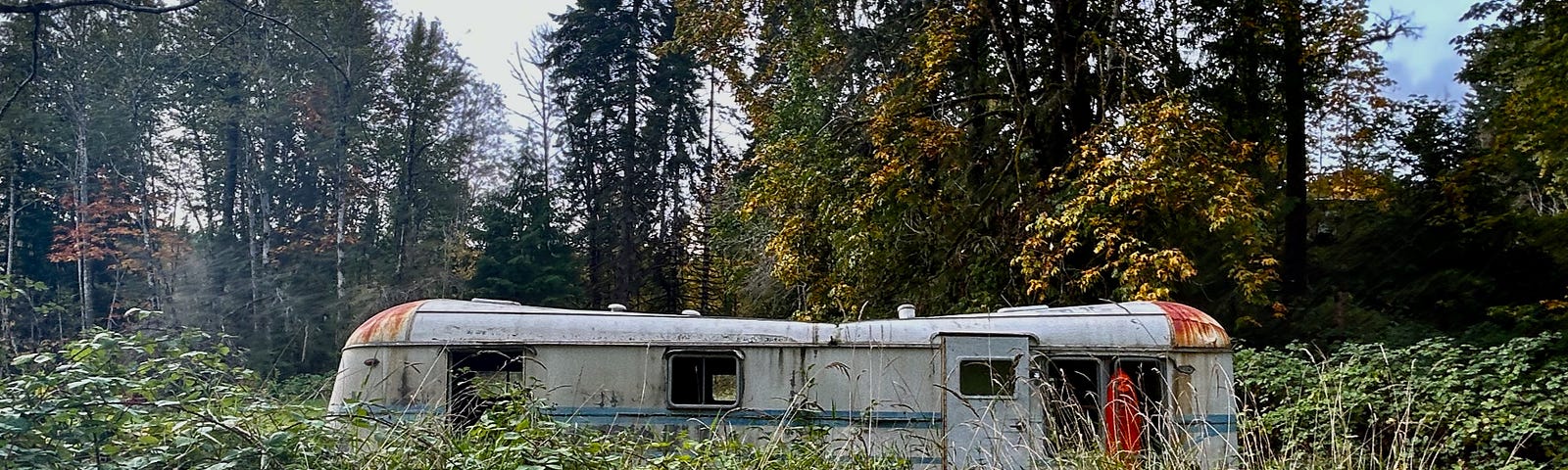 A photo of a trailer in a yard. The trailer is old and looks uninhabited.