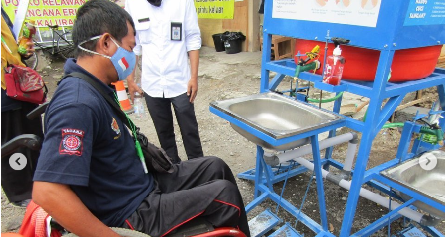 A man in a wheelchair testing an accessible handwashing station in Indonesia.