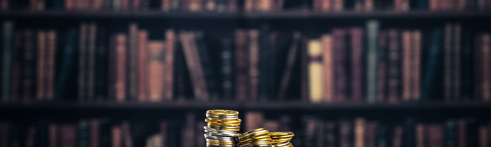 Stacks of coins sitting on top of an open book, on a table with a full bookshelf in the background