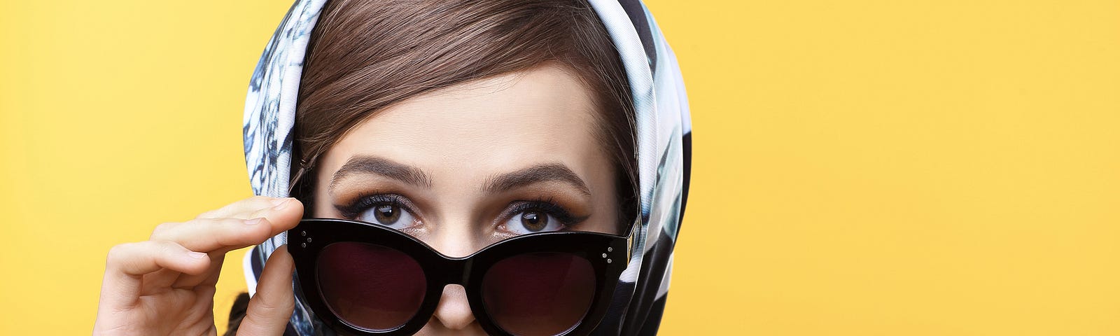 woman in ’60s scarf and sunglasses, yellow background.