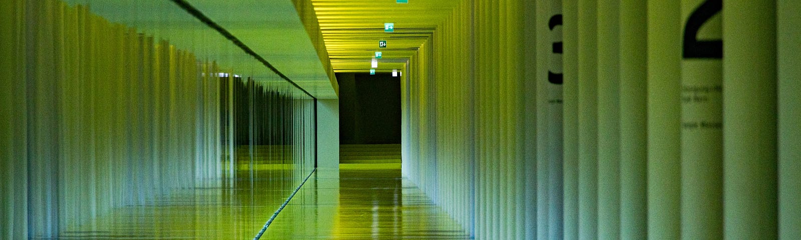 a long green hallway, bright and yet strange. A dark open door stands at the end.