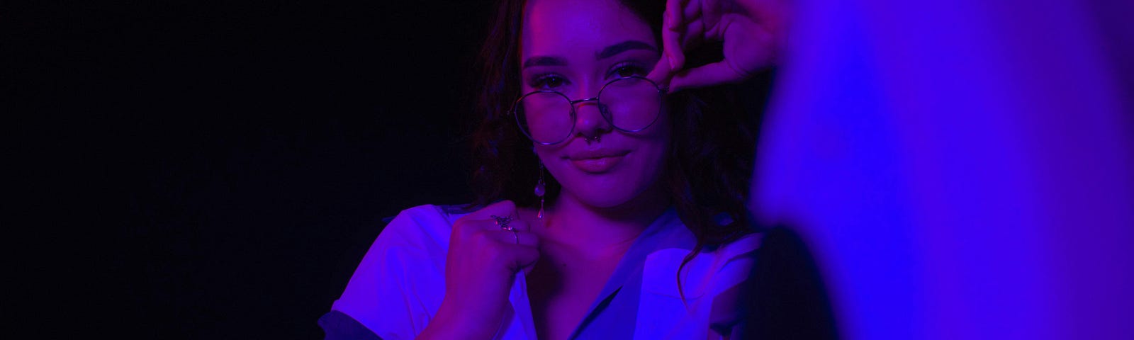 Young woman wearing glasses in purple light