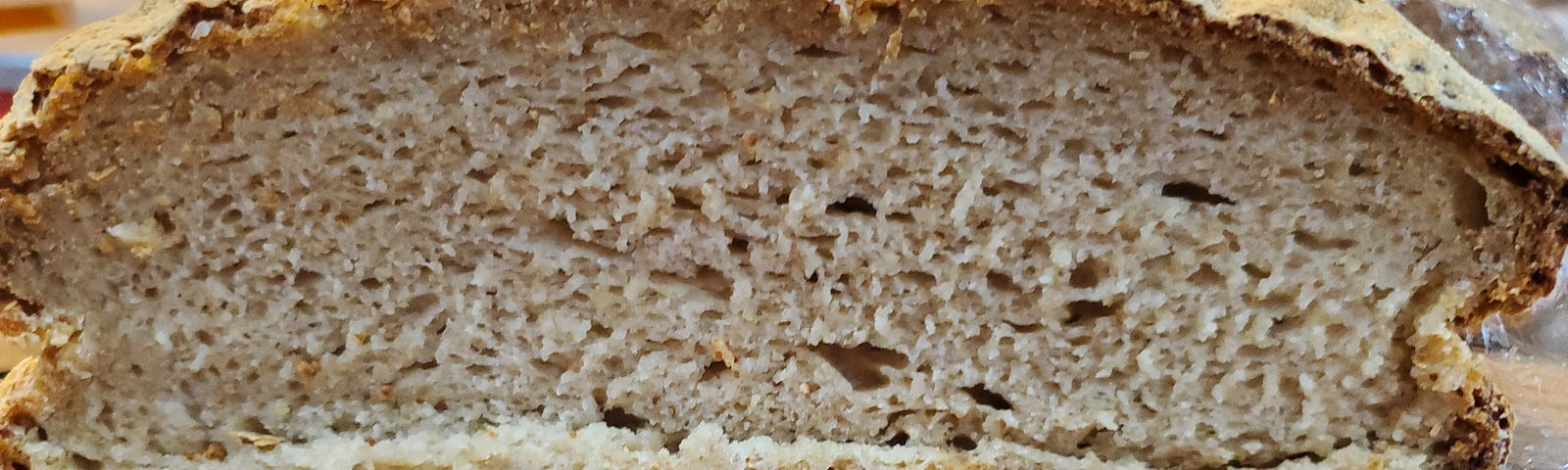 Loaf of gluten free sourdough bread on counter cut open to see inside.