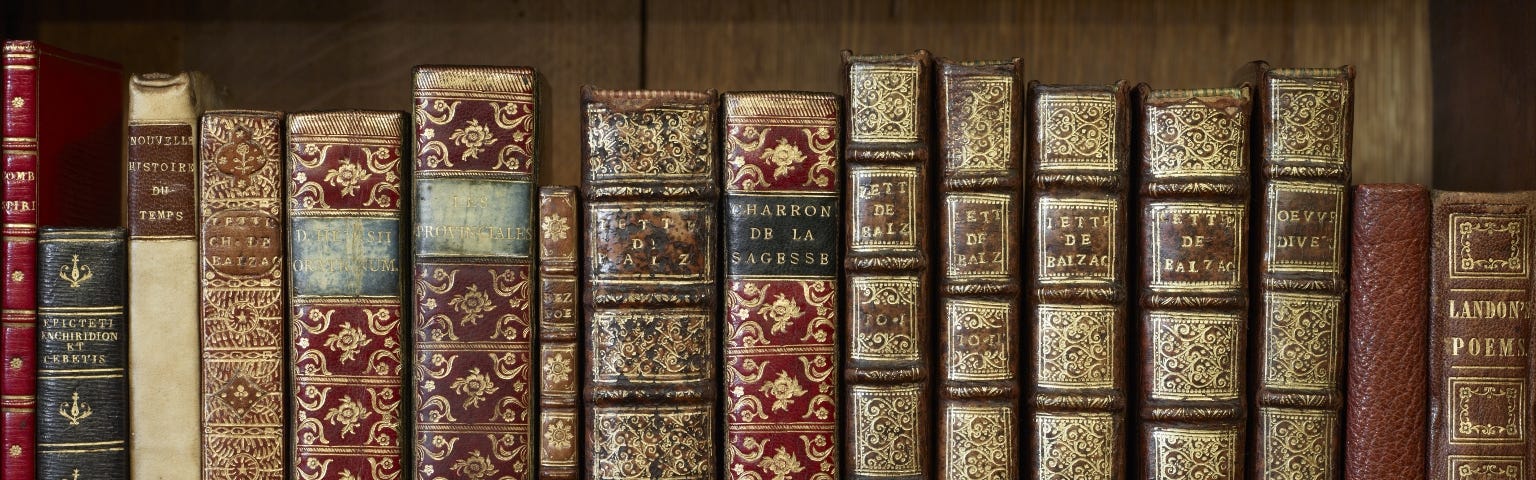 Row of antique volumes, standing upright, on a shelf