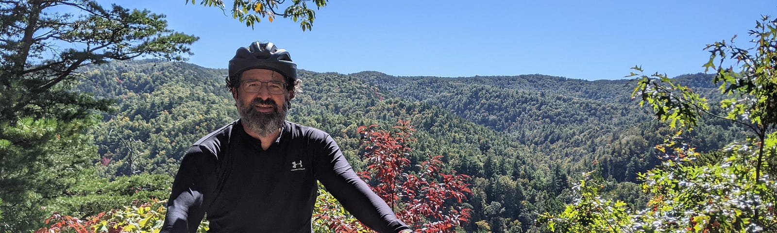 This shows a man with his bike in front of a forest.