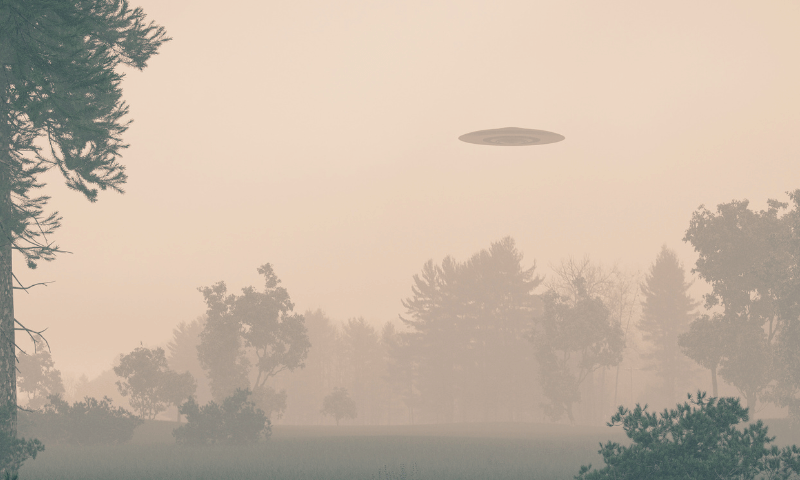 Sepia toned photo of a flying saucer above a meadow with trees.