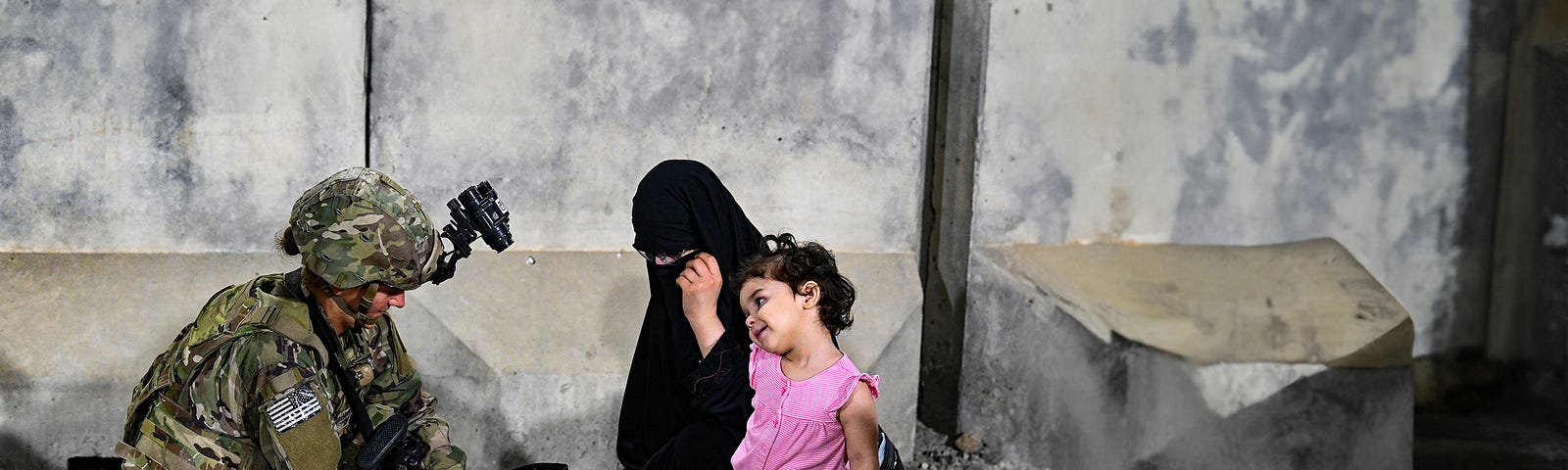 A U.S. paratrooper helps a woman and child evacuating from Afghanistan in August 2021. Photo by U.S. Central Command Public Affairs