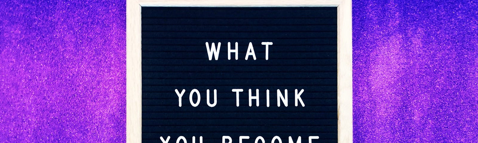 A board reads “what you think you become” against a purple background. Manifesting.