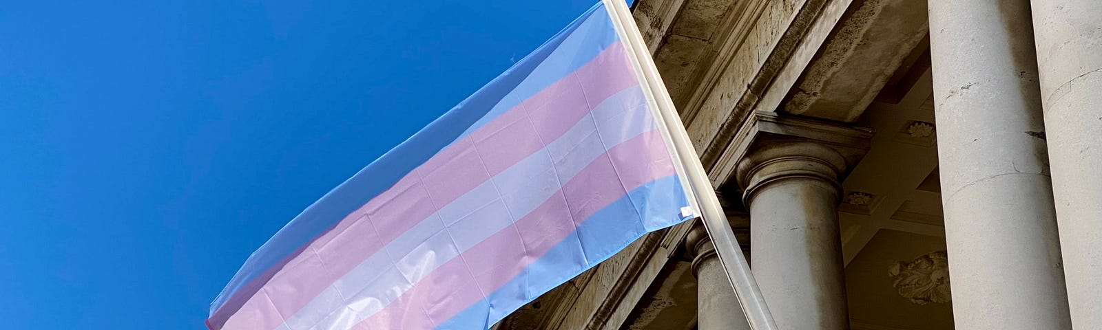 a trans flag fluttering in the sunshine at greenwhich uk