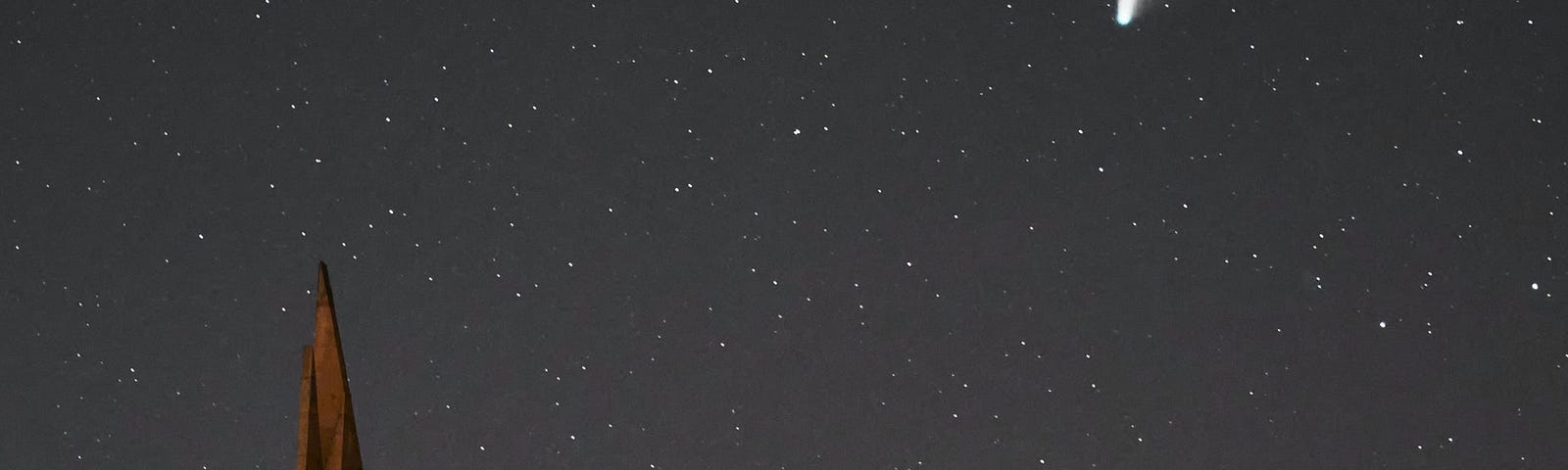 A comet falls in the background. In the foreground, a house appears lit against the stars