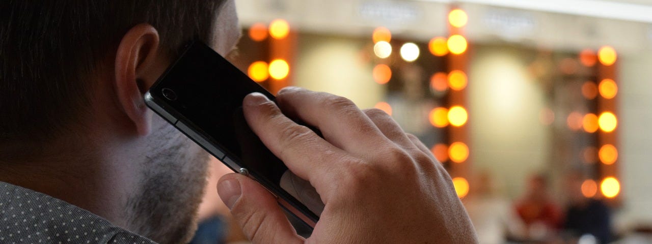 A man in his business office talking to a client on his cell phone. Using relationship marketing to bond with his clients.