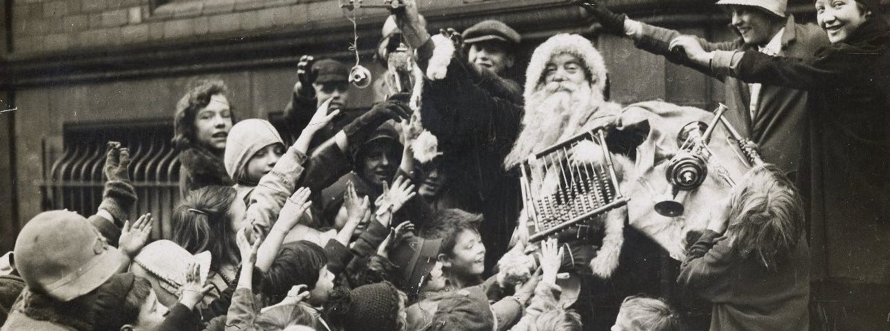 Black and white photograph of Father Christmas handing out presents to a crowd of children from the Wood Street Mission in Manchester in the 1930s