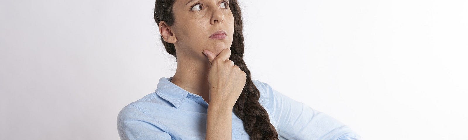 A young woman with a blue shirt thinking and wondering