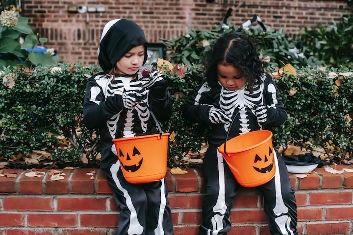 Photo of trick-or-treaters looking into candy bags. Humor. Funny. Halloween. Children. Candy. Parenting. Danger. Treats. Costumes. Masks.
