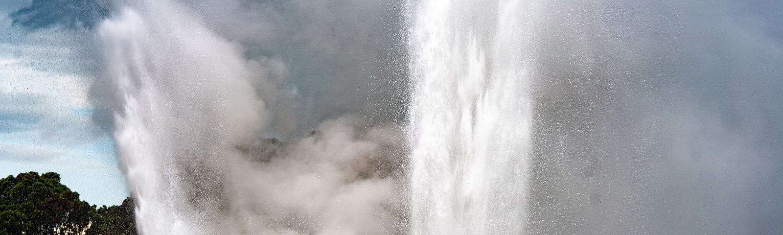 A geyser bursting up from the ground. Steam clouds all around the water.