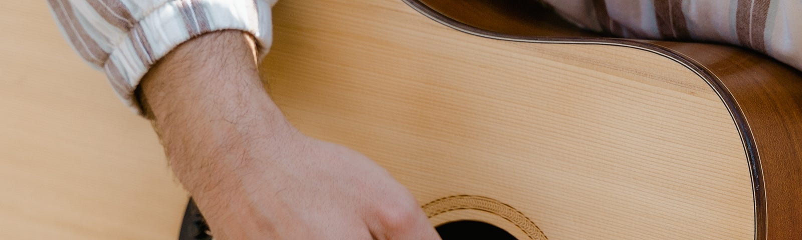 guy’s hand strumming an acoustic guitar