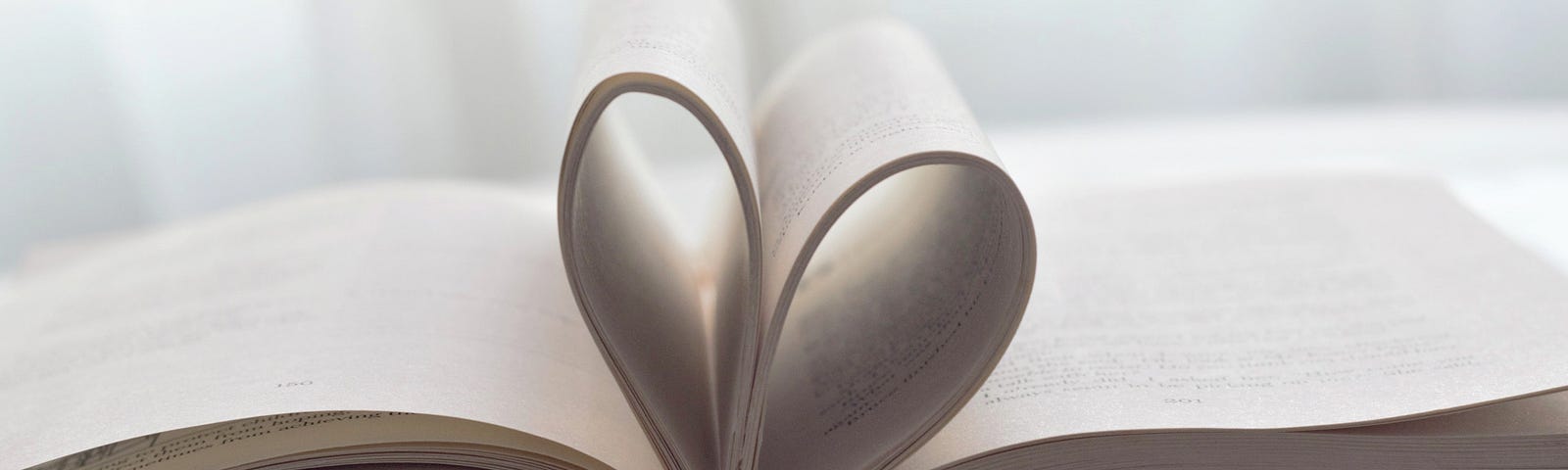 a book sits open and in profile; the middle pages are folded inwards to create a heart-shape