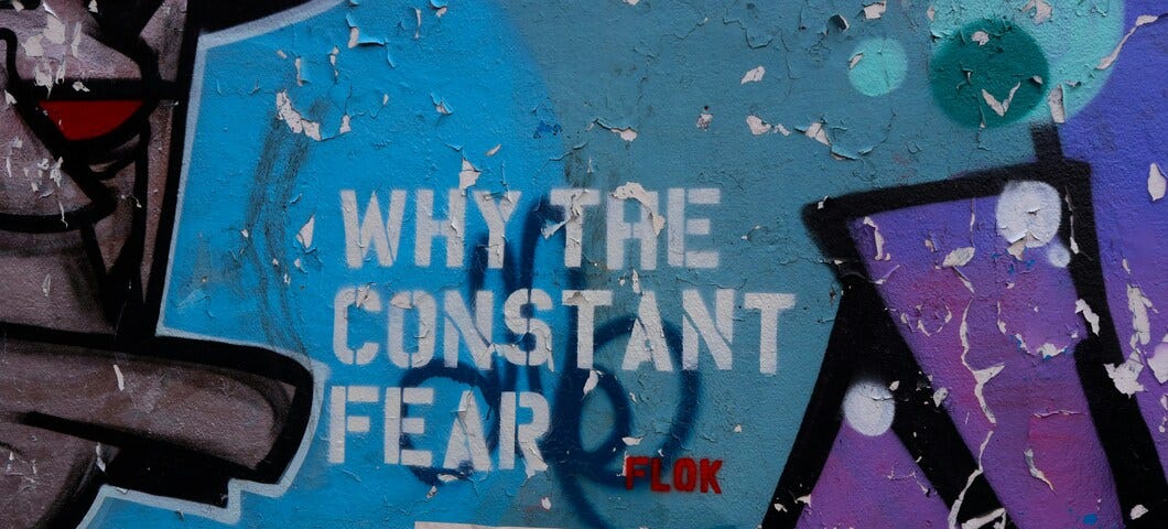 Graffiti on a wall with the words “Why the constant fear” stencilled onto the wall