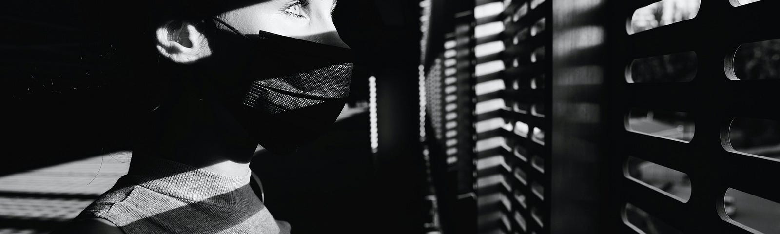 Someone scared and looking through blinds out of a window.