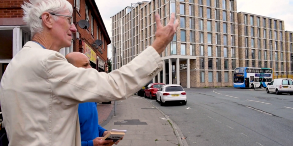 Piprani and Lindop looking out at a street, screenshot from video ‘Finding Green Hay’.