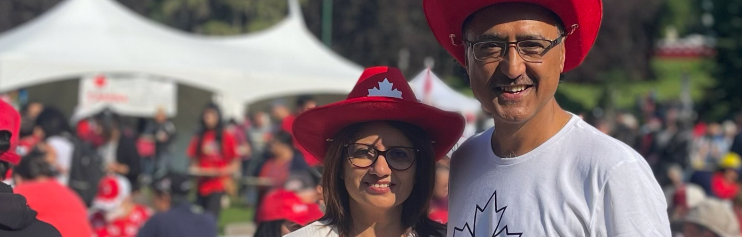Amarjeet Sohi and his wife, Sarbjeet in red cowboy hats on a sunny Canada Day.