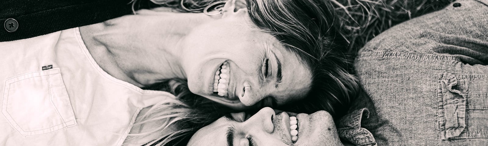 black and white photo of happy smiling couple laying on ground looking at each other