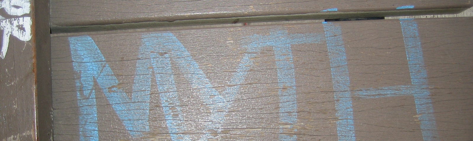 “Myth” written on the ground in blue color with white colored shoes besides it.