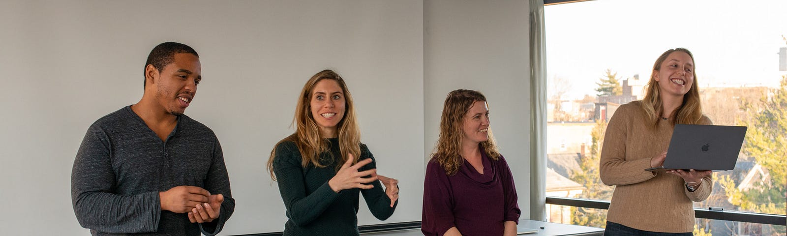 Four Assembly Fellows stand to present their work