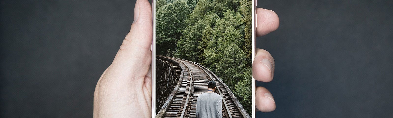 Image of a man walking along railroad tracks into a phone screen