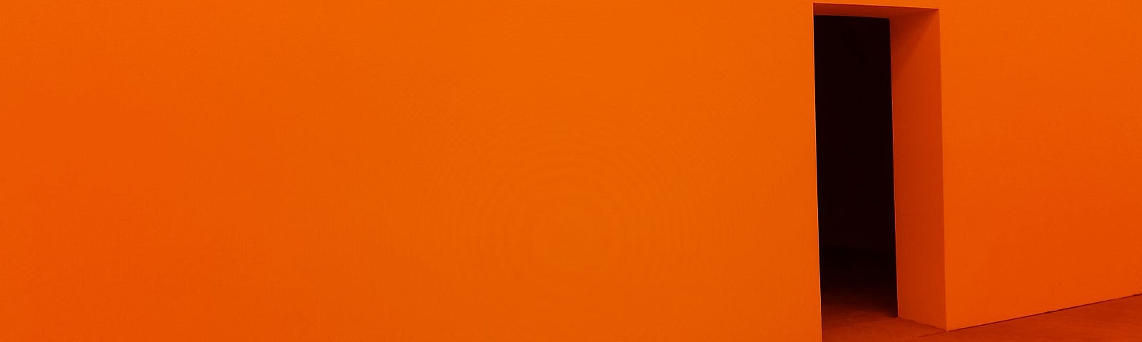 Foto com parede pintada na cor laranja e com abertura e chão de madeira em cor marrom
