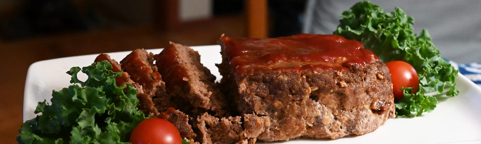 Cooked meatloaf which has been plated, sliced, and garnished.