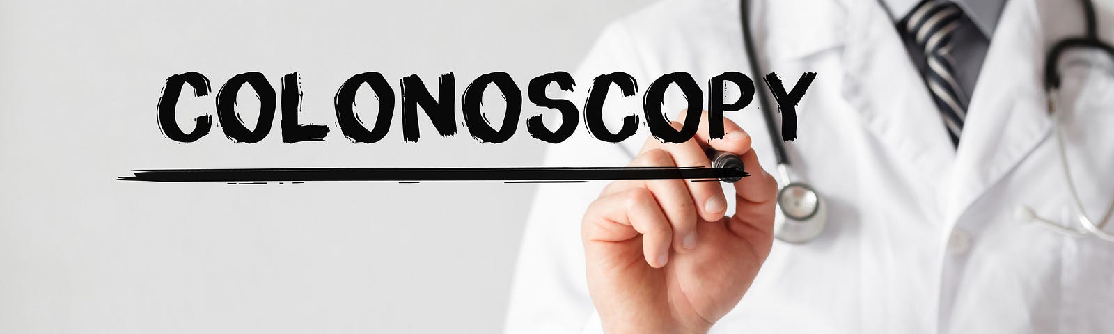 A doctor faces us as he writes the word COLONOSCOPY on a glass pane. Furthermore, colonoscopy plays a crucial role in preventive medicine by enabling the removal of precancerous polyps during the procedure, effectively reducing the risk of developing colorectal cancer.