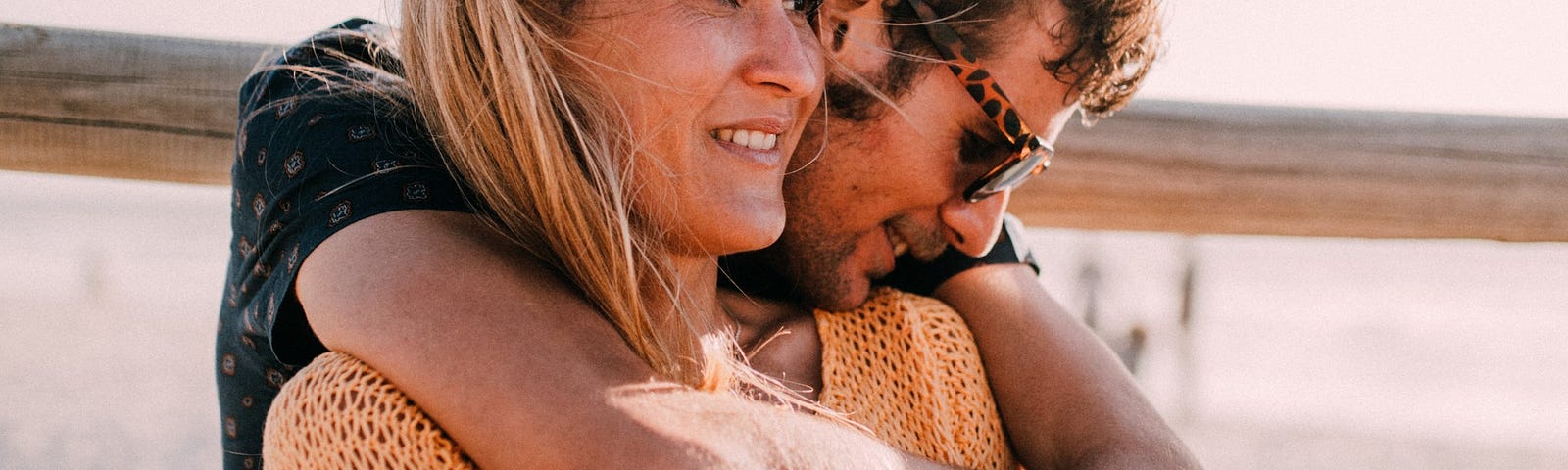 A smiling couple embraces in the sunlight.