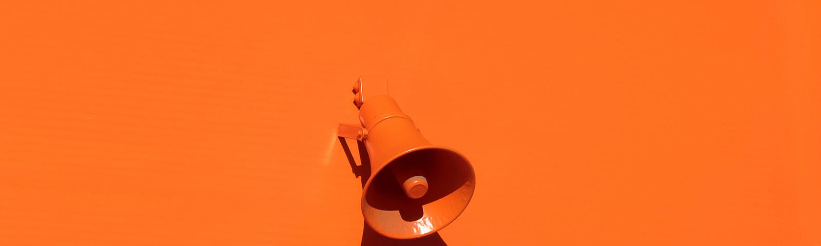 A photo of an orange bullhorn on an orange background