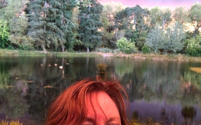 woman stands in front of pond.