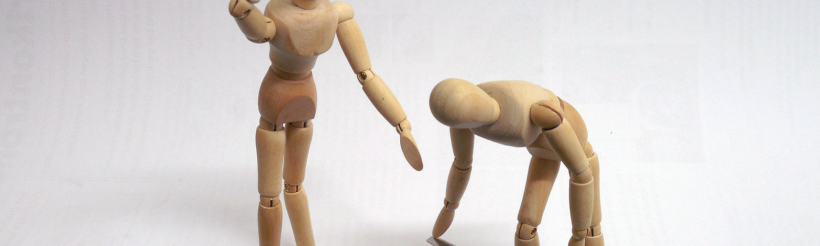 Two wooden painting figures (mannequins) are trying to get to a computer keyboard tied with a chain and locked with a padlock