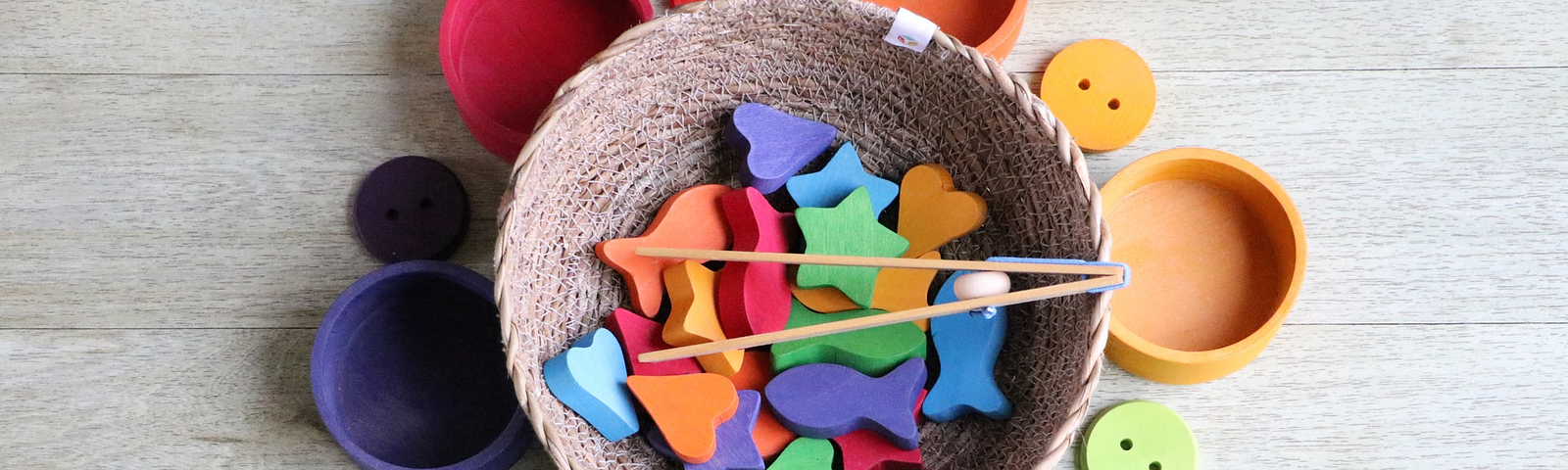 a basic filled with brightly colored shapes with chopsticks surrounded by brightly colored bowls and buttons