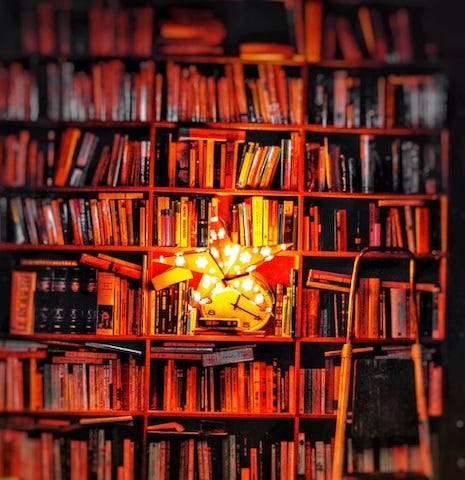 a brightly lit decorative star leans on a bookshelf of many books in a library. There is a step ladder leaning on the shelf