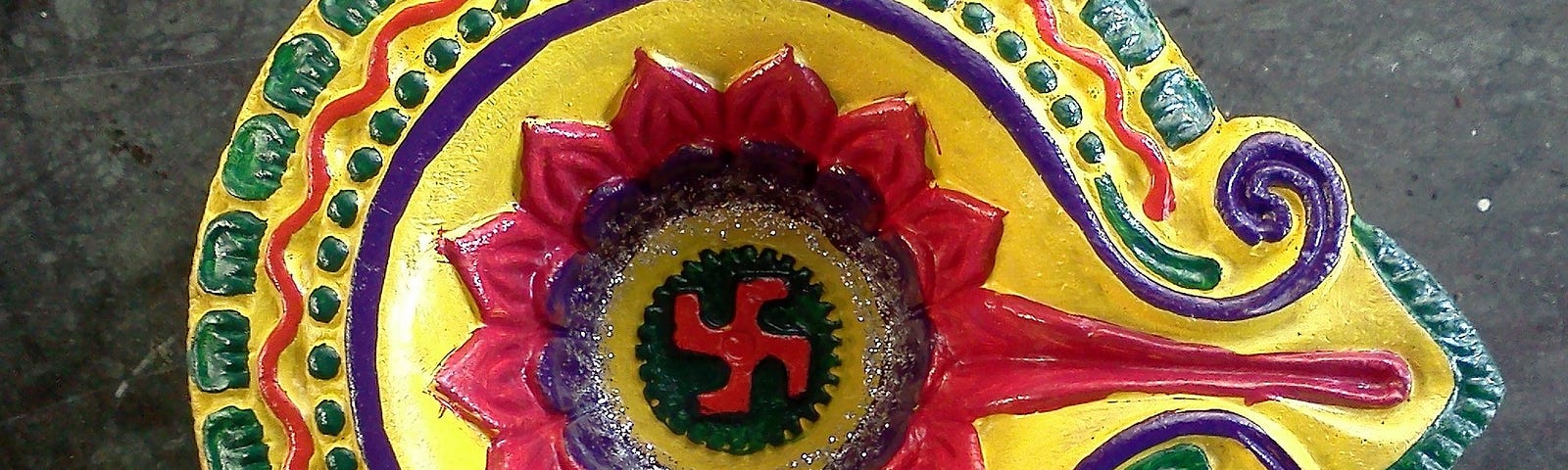 brightly painted bowl with a Hindu four armed cross in the centre