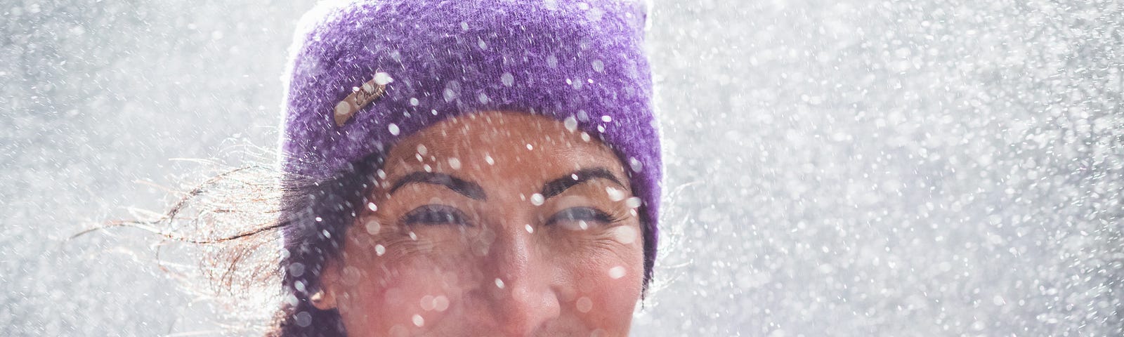 A woman smiling with snowflakes all around her.