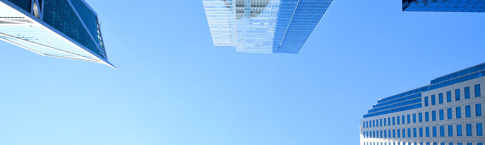 Photo of bright blue and cloudless sky with glass and concrete high-rise buildings framing the edges